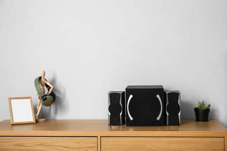 Modern speakers, headphones and blank photo frame on wooden table near light wallの写真素材
