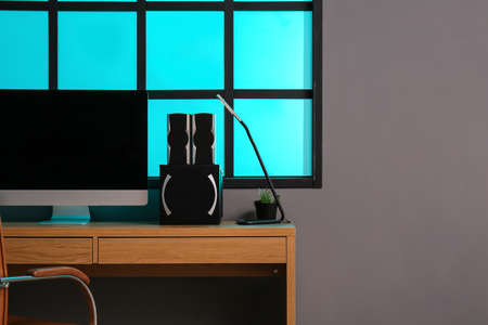Workplace with modern computer and speakers near gray wall