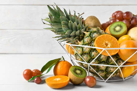 Basket with juicy fruits on white wooden background, closeupの写真素材