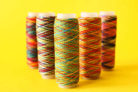 Rainbow sewing thread spools on color background
