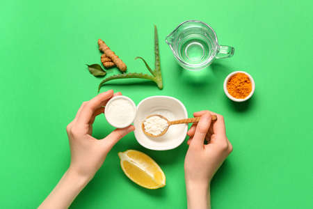 Woman making turmeric mask on green backgroundの写真素材