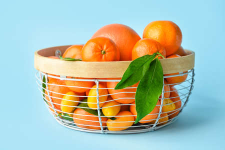 Basket with fresh juicy fruits on color background