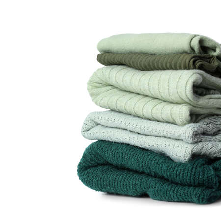 Stack of knitted sweaters on white background, closeup