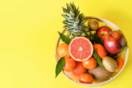 Basket with fresh juicy fruits on color backgroundの写真素材
