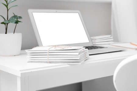 Stack of letters on table with modern laptop