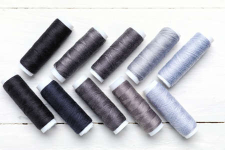 Sewing threads on light wooden background