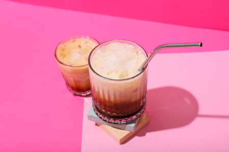 Glasses of White Russian cocktail on pink background