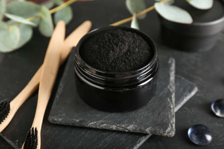Jar with activated charcoal tooth powder on black backgroundの写真素材