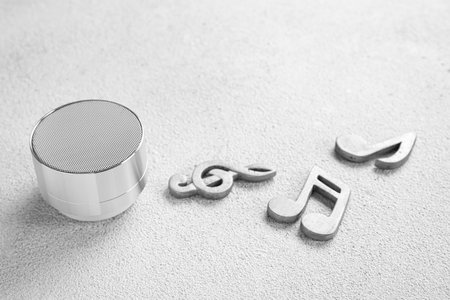 Modern wireless portable speaker and music notes on light backgroundの写真素材