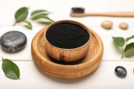 Bowl with activated charcoal tooth powder on white wooden backgroundの写真素材