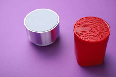 Modern wireless portable speakers on purple background