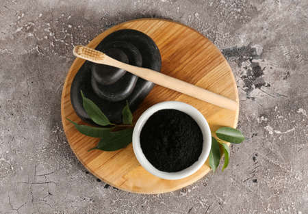 Bowl with activated charcoal tooth powder and stones on gray backgroundの写真素材