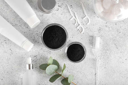 Bowls with activated charcoal tooth powder, brush and different cosmetic on light backgroundの写真素材