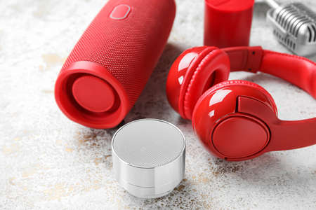Different wireless portable speakers and microphone on grunge background
