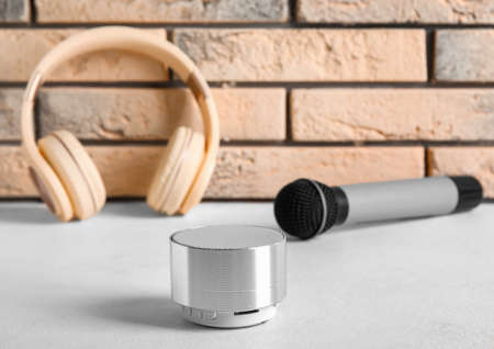 Wireless portable speaker, headphones and microphone near light brick wallの写真素材