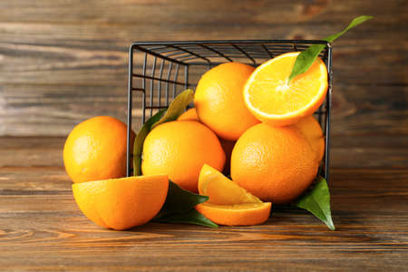 Basket with fresh juicy oranges on wooden background
