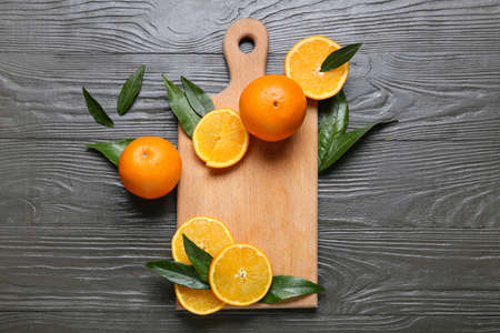 Board with fresh juicy oranges on brown wooden background