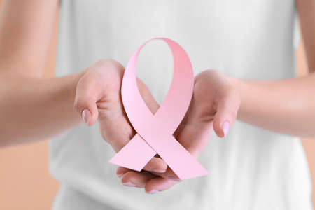 Young woman with pink ribbon on color background, closeup. breast cancer awareness conceptの写真素材