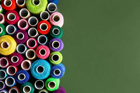 Set of different spools with sewing threads on green background