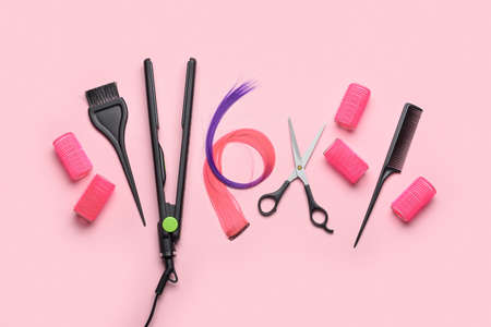 Hairdresser's tools, hair strands and curlers on pink backgroundの写真素材