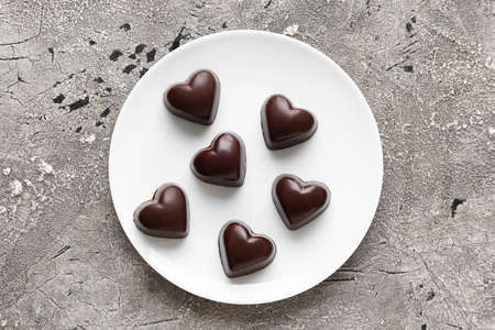 Plate with tasty heart-shaped candies on gray backgroundの写真素材