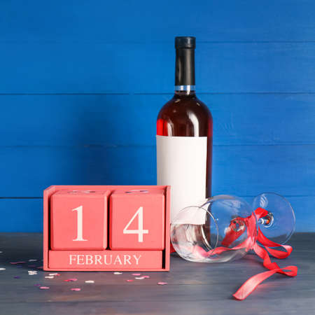 Calendar with date of Valentines Day, wine bottle and glass on tableの写真素材