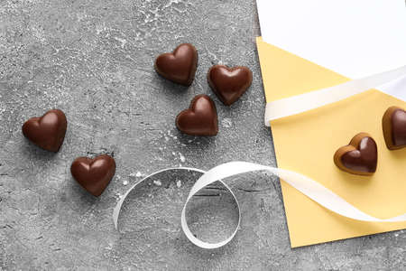 Tasty heart-shaped candies and envelope on gray background