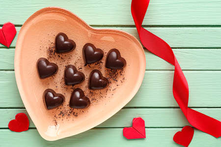 Box with tasty heart-shaped candies on color wooden background