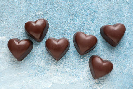Tasty heart-shaped candies on color background