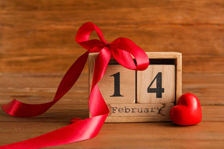 Calendar with date of Valentines Day, plastic heart and red ribbon on wooden backgroundの写真素材