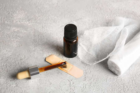 Bottle with iodine, pipette, medical plaster and gauze roll on grunge backgroundの写真素材