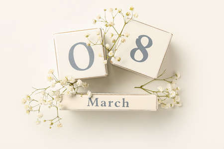 Calendar with date of International Women's Day and flowers on white background