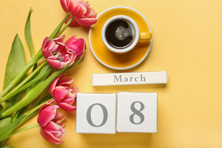 Calendar, cup of coffee and flowers for International Women's Day celebration on yellow backgroundの写真素材