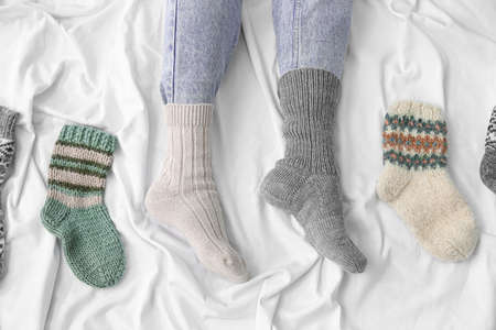 Female legs in different warm socks on bed. Concept of heating seasonの写真素材