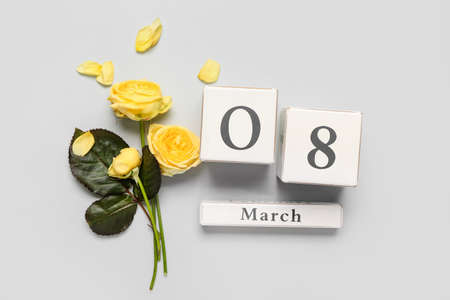 Calendar with date of International Women's Day and flowers on gray background