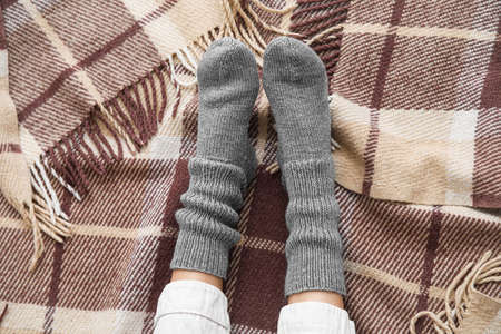 Female legs in warm socks on plain. Concept of heating season