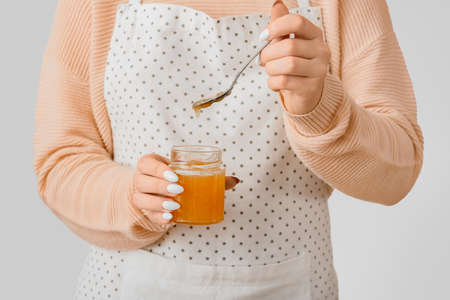 Woman with jar of tasty orange jam on light backgroundの写真素材