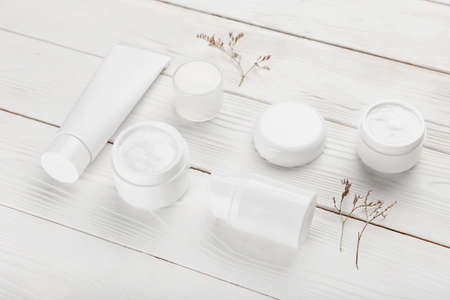 Composition with jars of natural cosmetic cream on light wooden background
