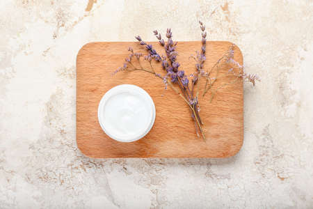 Jar with natural cosmetic cream and flowers on light backgroundの写真素材