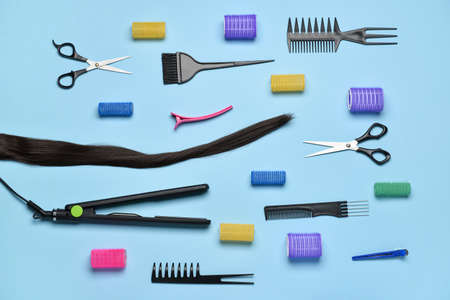 Composition with hair strand, hairdresser's tools and curlers on blue backgroundの写真素材