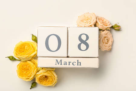 Calendar with date of International Women's Day and flowers on white background