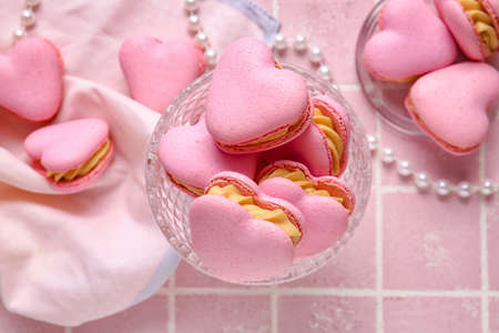 Dessert bowl with tasty heart-shaped macaroons on pink background, closeupの写真素材