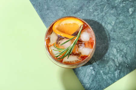 Glass of delicious Old Fashioned Cocktail on green background