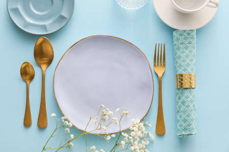 Elegant table setting with flowers on blue background