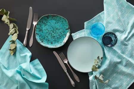 Elegant table setting with eucalyptus leaves on dark background