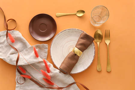 Elegant table setting with flowers on orange background