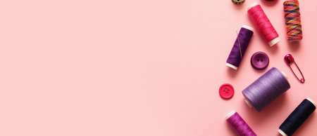 Colorful sewing threads and buttons on pink background with space for textの写真素材