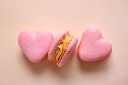 Tasty heart-shaped macaroons on beige background