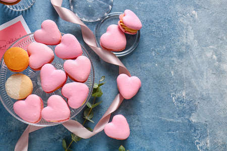 Dessert stand with tasty heart-shaped macaroons on blue backgroundの写真素材