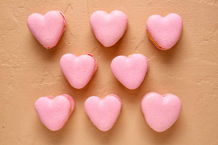 Tasty heart-shaped macaroons on beige background